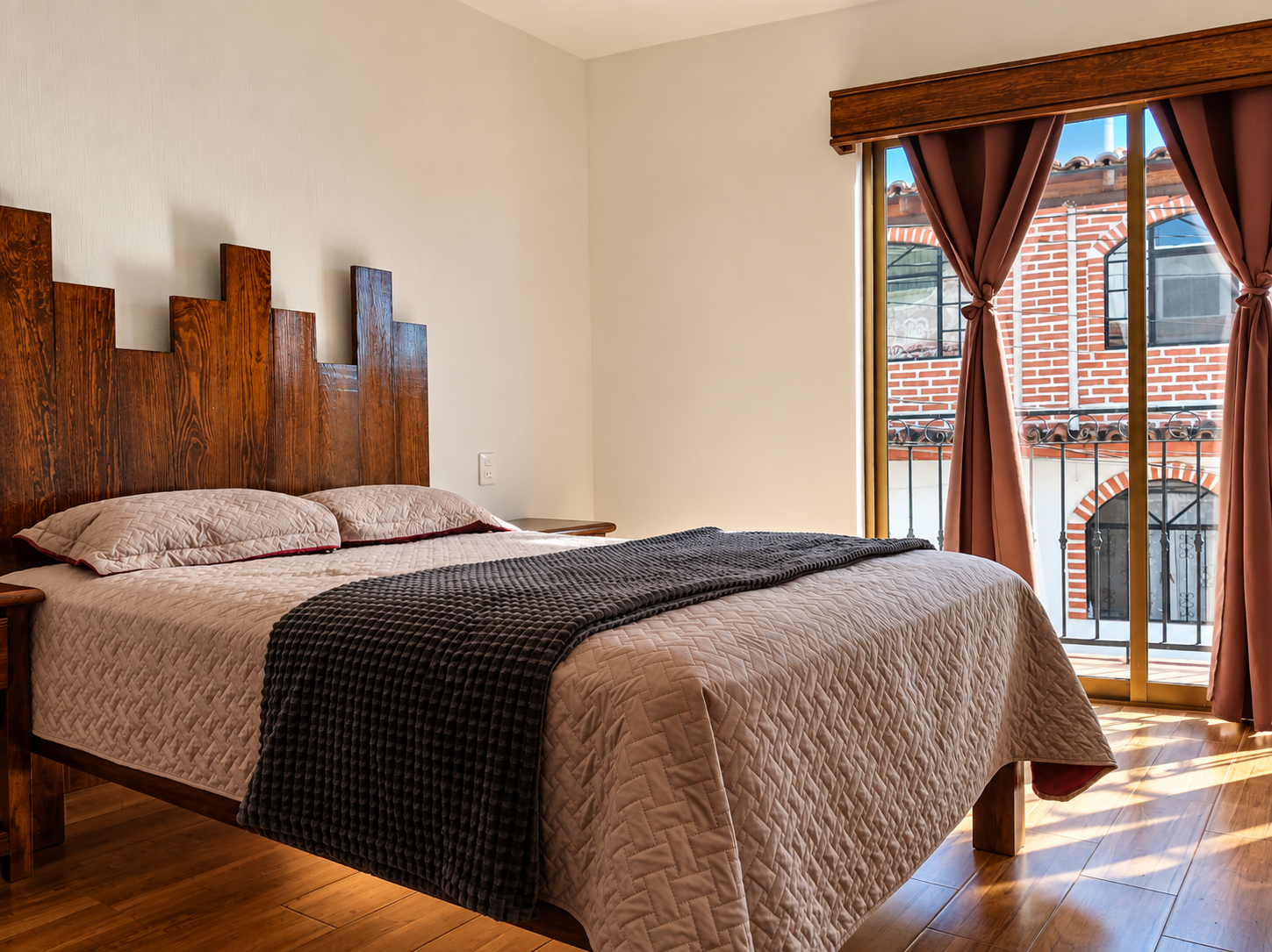 Habitación con cabecera de madera, textiles cálidos y balcón
